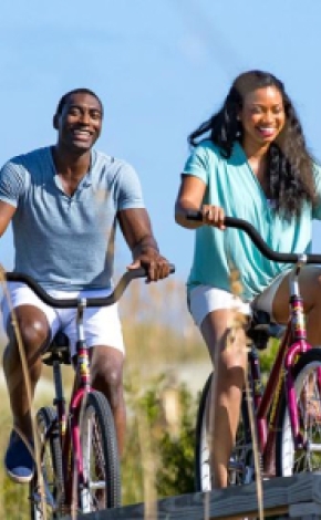 A man and woman bike along a boardwalk.
