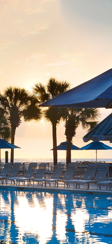 pool with umbrella's and sunrise in the background